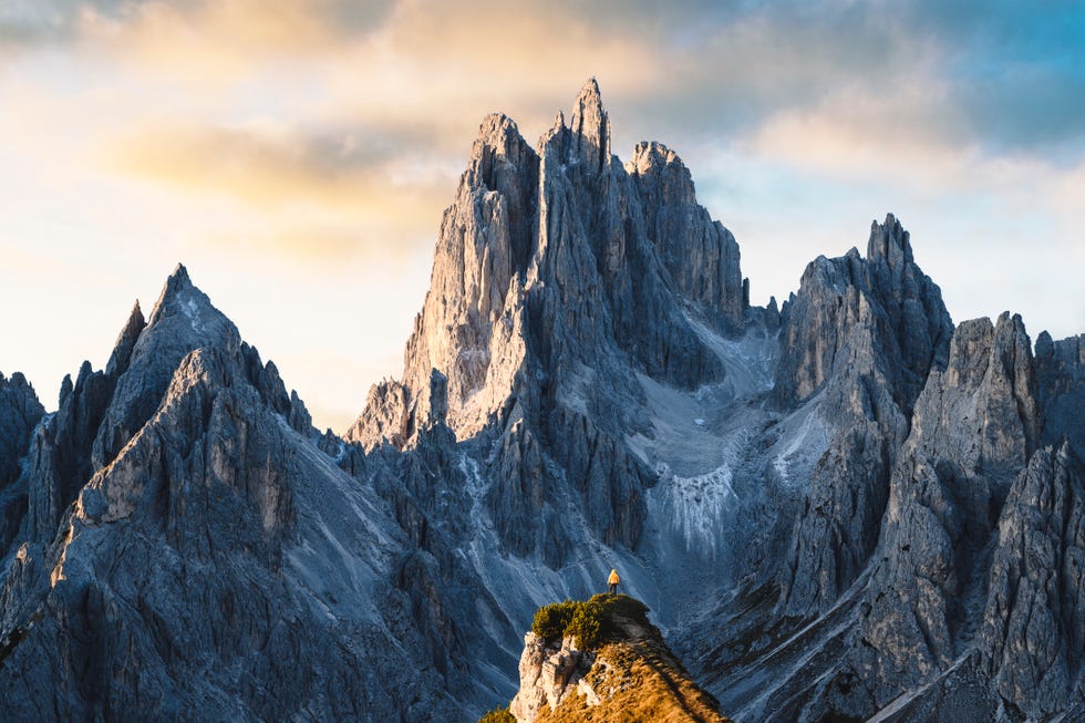 one person standing in front of sharp dolomites peaks, italy