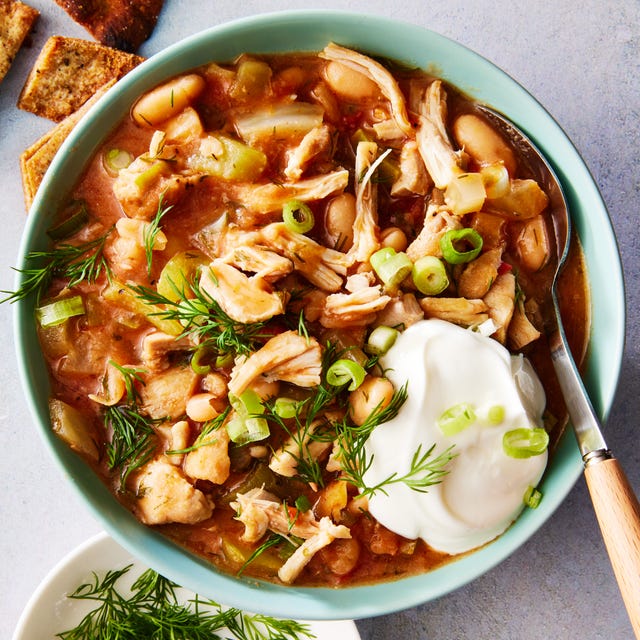 chili in a bowl with chicken, tomatoes, and green onions