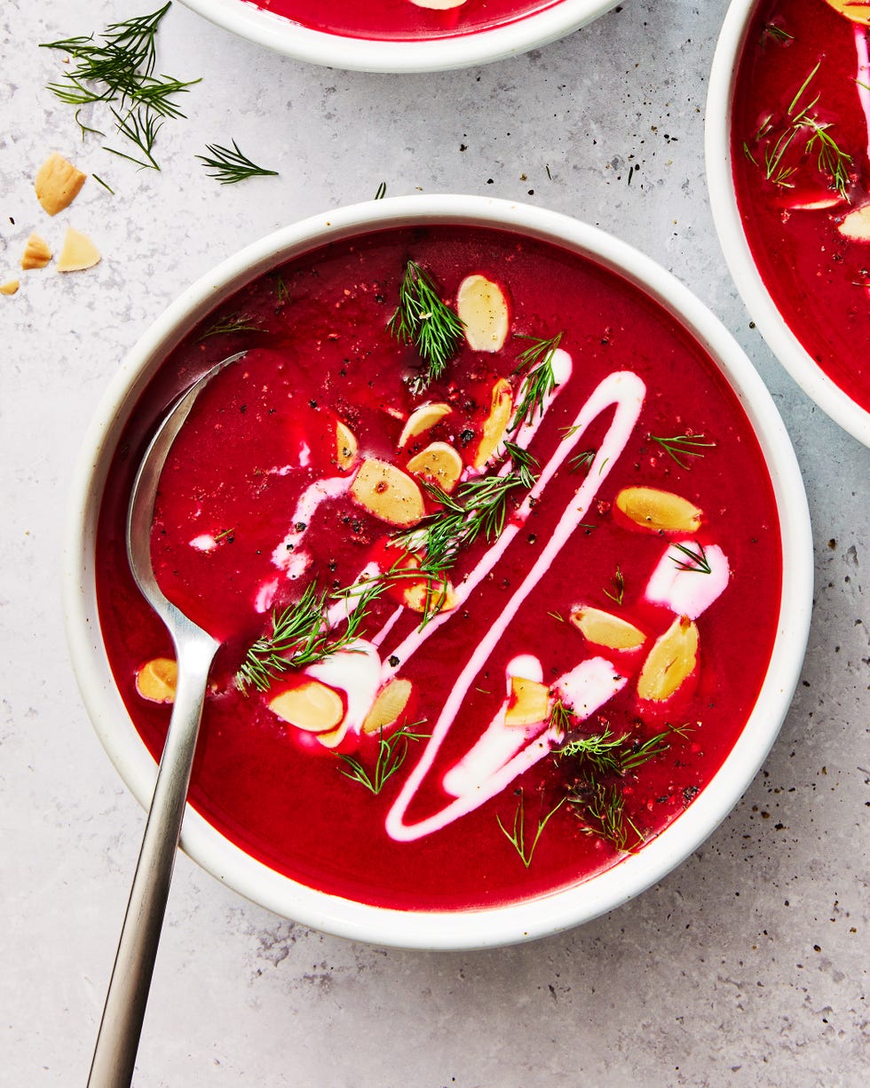 one pot harissa beet soup in a white bowl topped with almonds, herbs, and cream