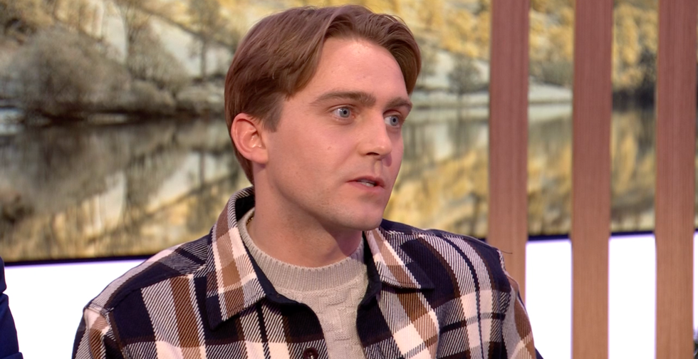 barney walsh on the one show, a man wears a plaid jacket and sweater seated on a chat show set