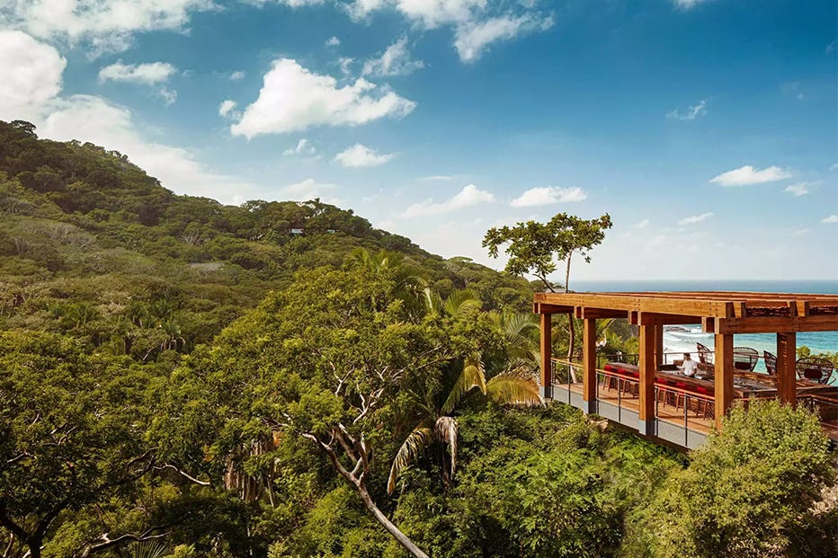 scenic view of a modern wooden structure overlooking lush greenery and ocean scenic view of a modern wooden structure overlooking lush greenery and ocean
