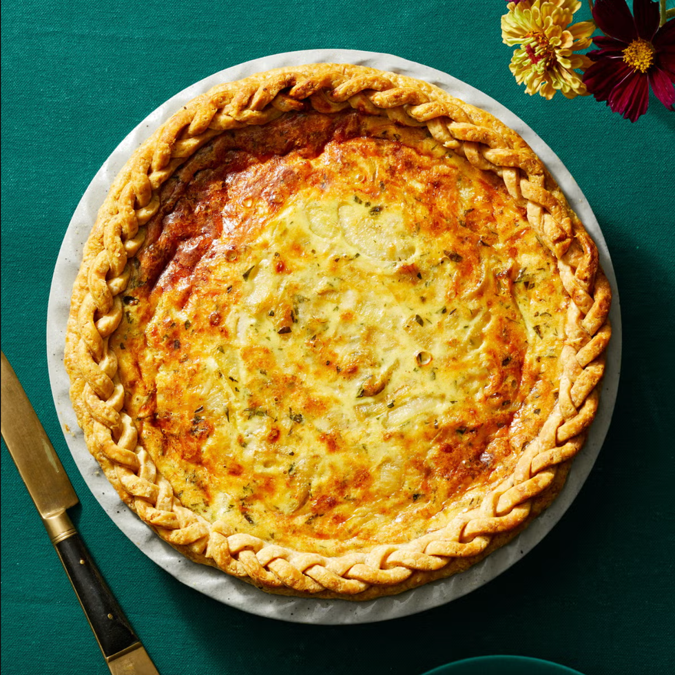 onion and gruyere quiche with braided crust all on a green background