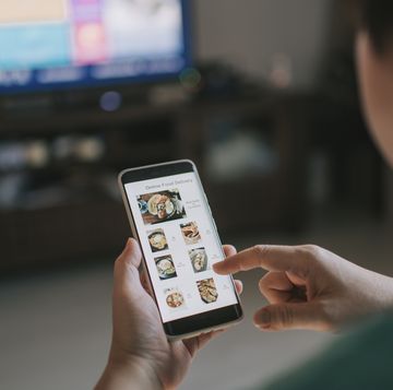 online food delivery mobile app shown on smart phone screen hold by asian woman hands in living room