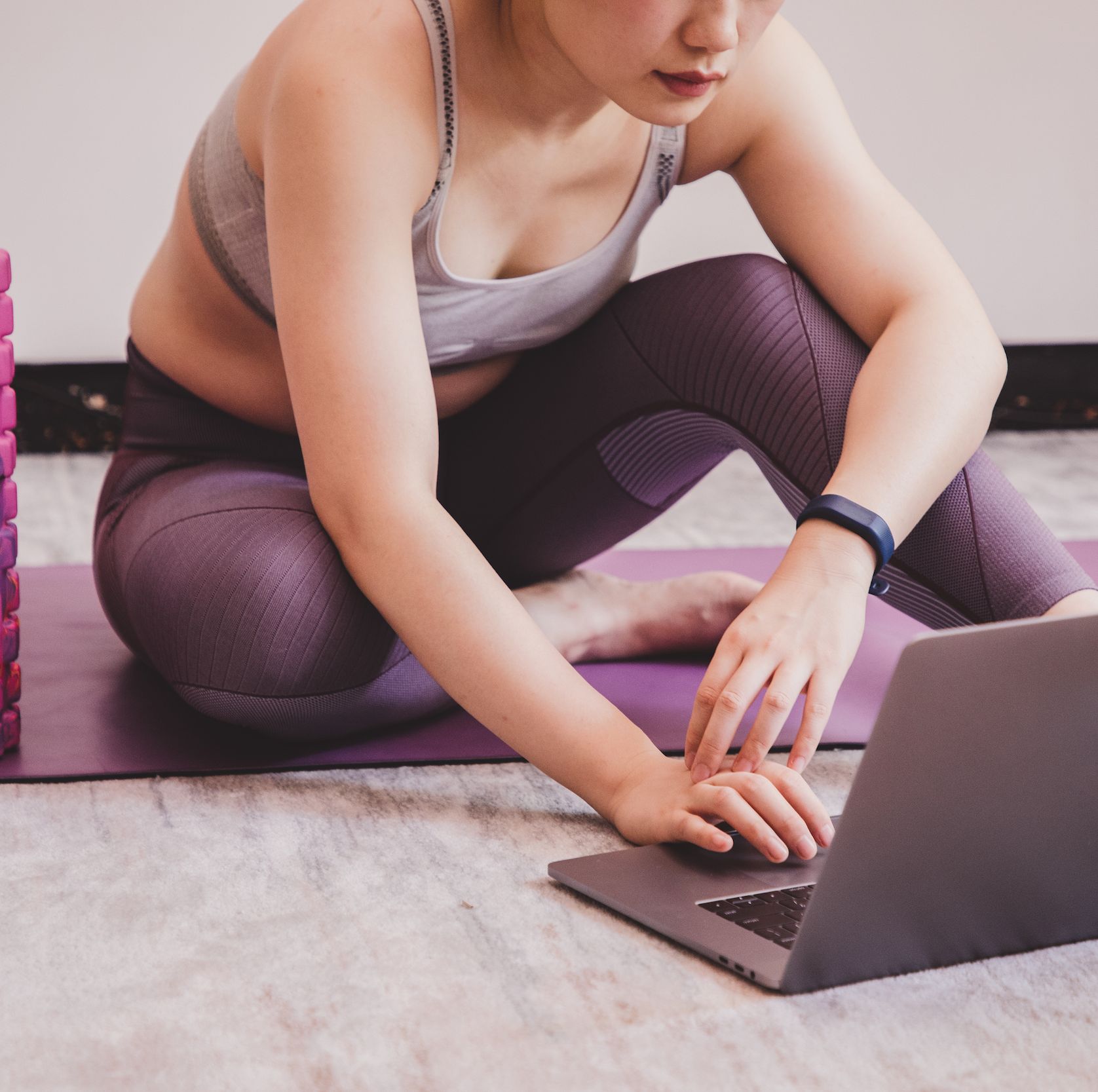 online personal training sessions review before and after results picture shows a woman sat on a yoga mat, looking at her laptop