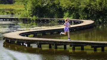 vrouw loopt over houten steiger over water