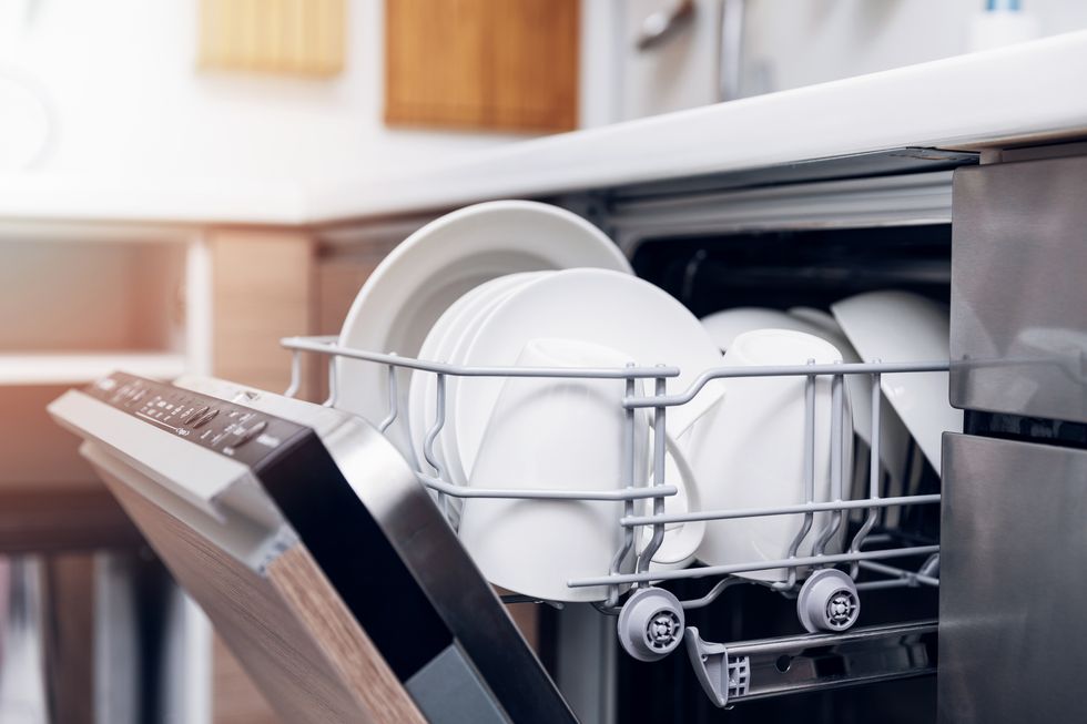 An open dishwasher with clean dishes in the home kitchen