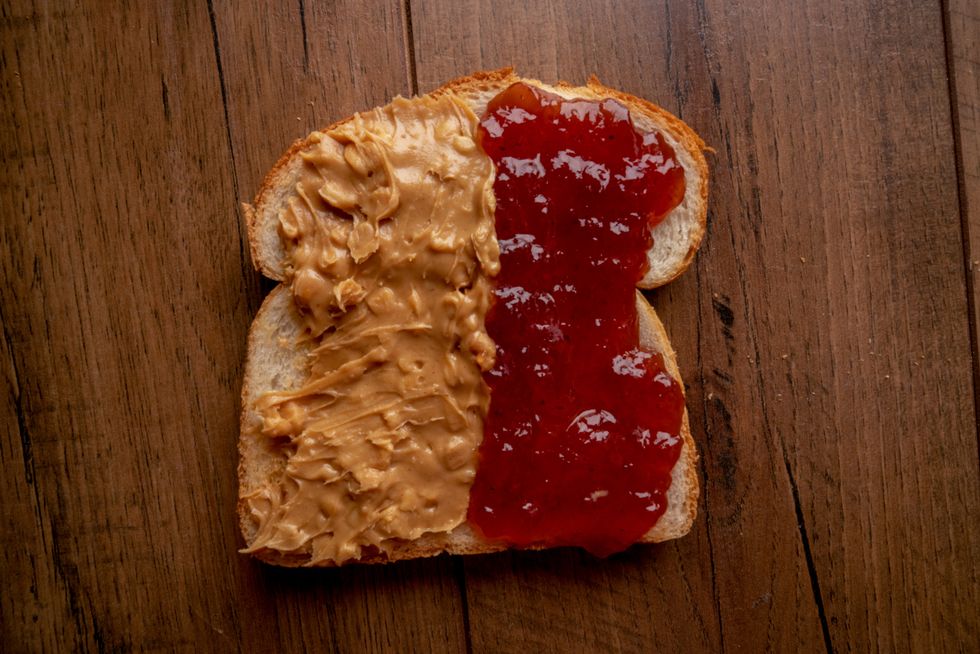 open face peanut butter and jelly sandwich on a rustic cutting board