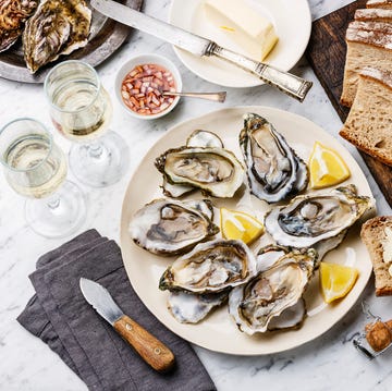 Open shucked Oysters with bread, butter and champagne on white marble background