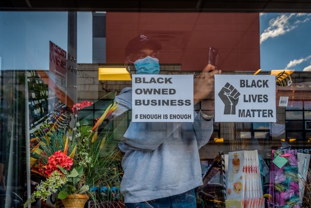 open storefront displaying a black owned business sign