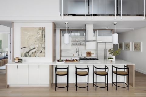 white kitchen with pendant lights and stools at counter
