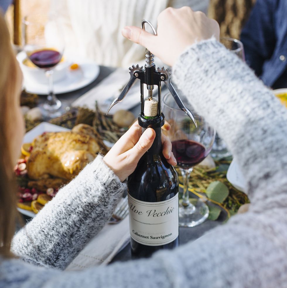 woman opening bottle of wine at thanksgiving
