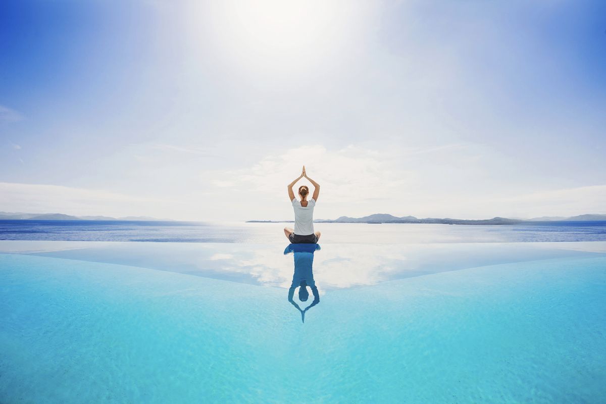 young woman meditating on infinity pool girl is practicing yoga with sea view at background relaxation exercises, yoga, balance, self care, healthy lifestyle concept
