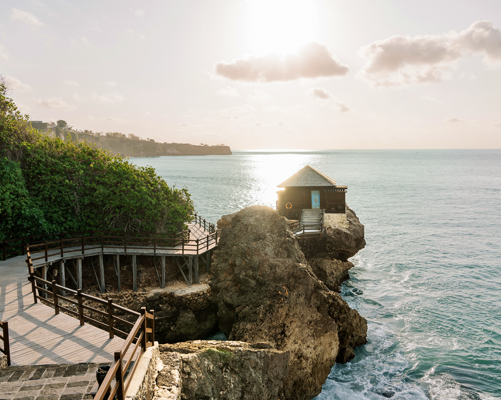 coastal scene featuring a wooden walkway leading to a small house on a rocky outcrop by the sea coastal scene featuring a wooden walkway leading to a small house on a rocky outcrop by the sea