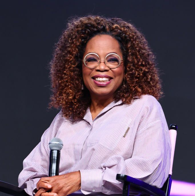 oprah winfrey pictured smiling sitting on stage with a microphone