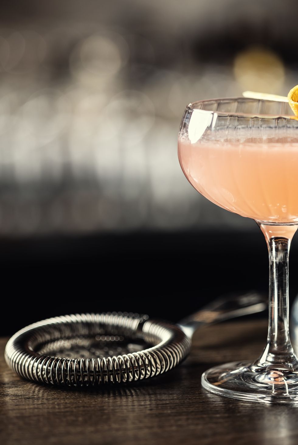 orange alcoholic cocktail drink cosmopolitan decorated with orange peel on bar counter.