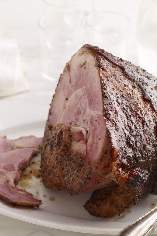orange coriander glazed ham sliced on a white platter