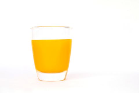 orange juice in glass against white background