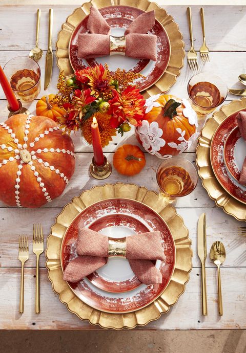 orange pumpkins decorated with lace as a centerpiece with napkins tied into bows on orange and white plates