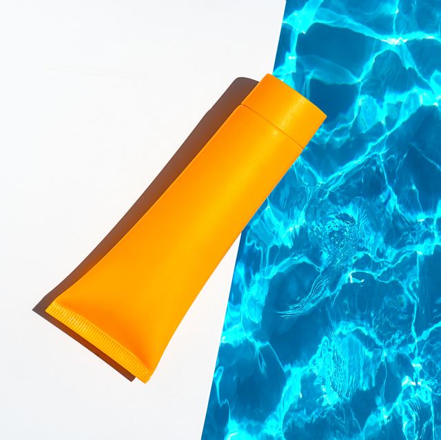 orange tube with suntan lotion, cosmetic face cream or hand cream, shower gel, shampoo against the background of blue turquoise water with waves from the swimming pool