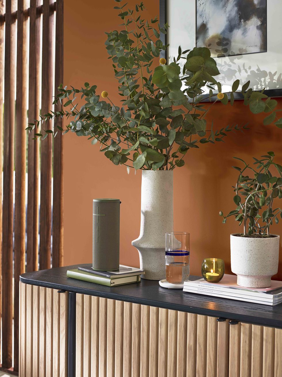 orange wall with natural accessories and a wooden side table