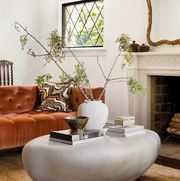 living room with orange sofa, fireplace and stone coffee table