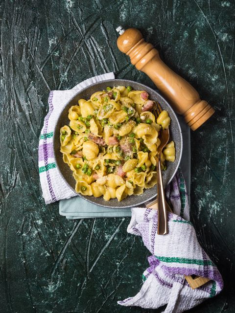 orecchiette pasta served in a bowl with spring peas, pancetta, and grated cheese