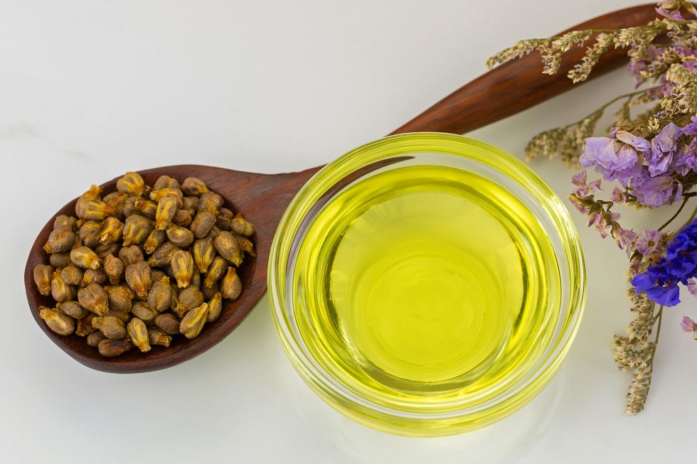 Organic cold pressed grapeseed oil in clear bowl with dried grape seeds in wooden spoon