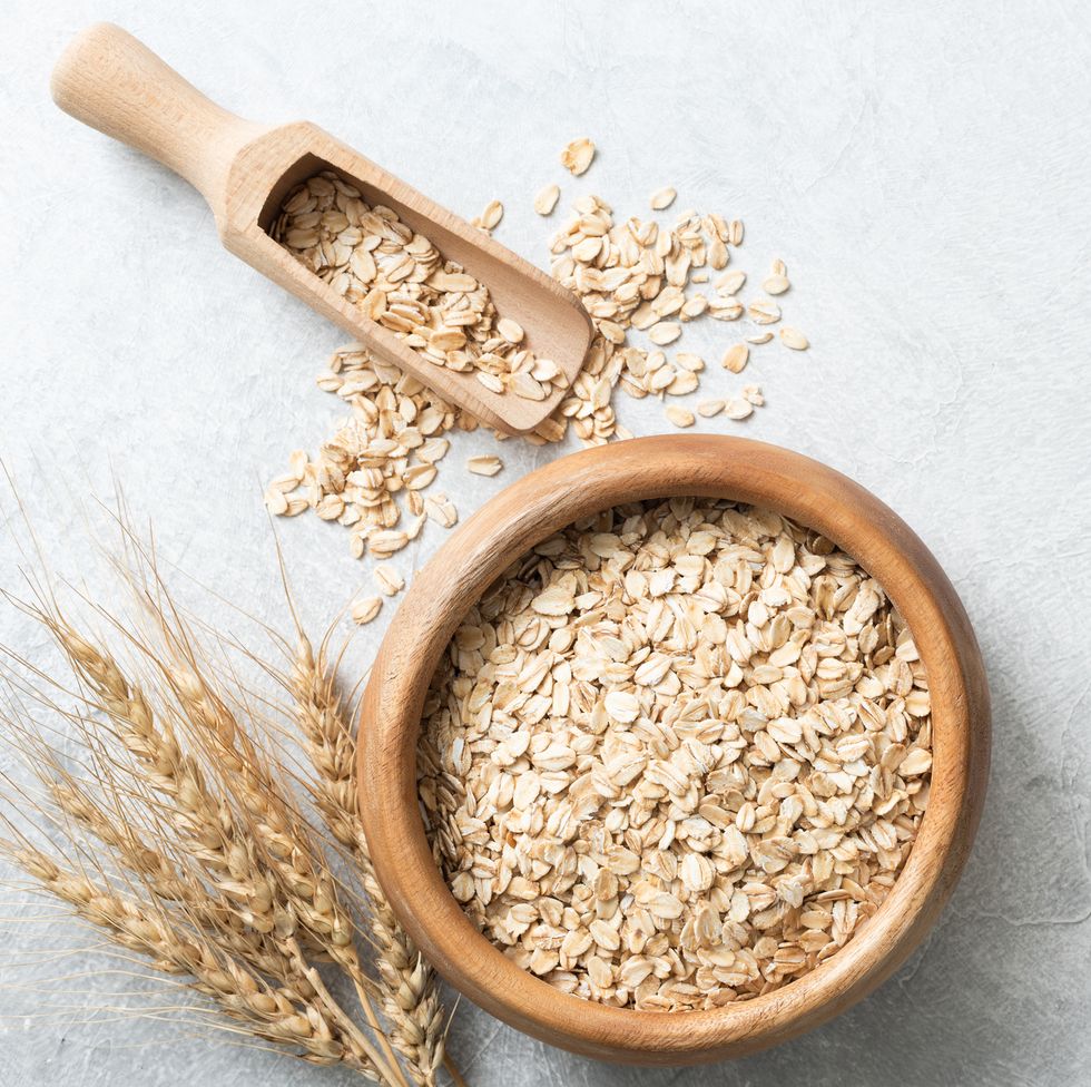 Organic rolled oats in wooden bowl on concrete background