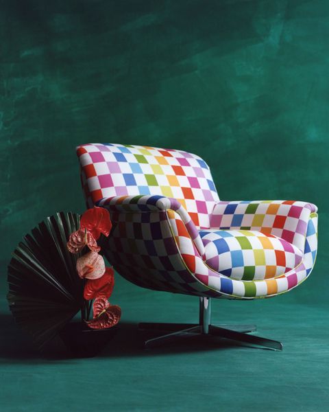 a curved chair with a metallic base upholstered in a checkered rainbow print