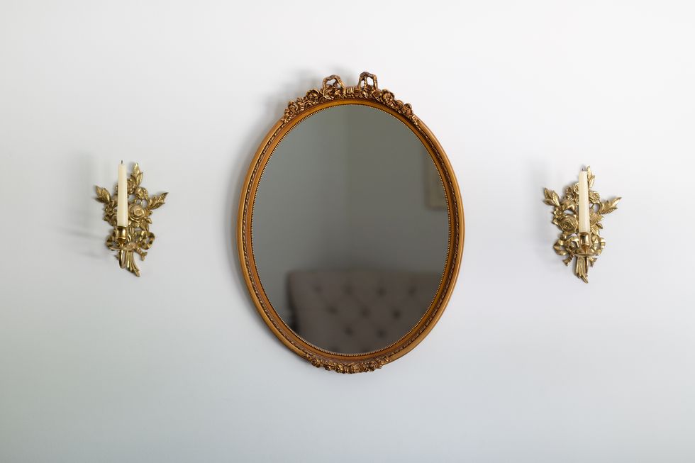 ornate oval wall mirror with side brass candle scones