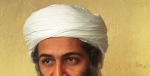 osama bin laden looks right of the camera, he wears a white turban and white top, he has a full mustache and long beard