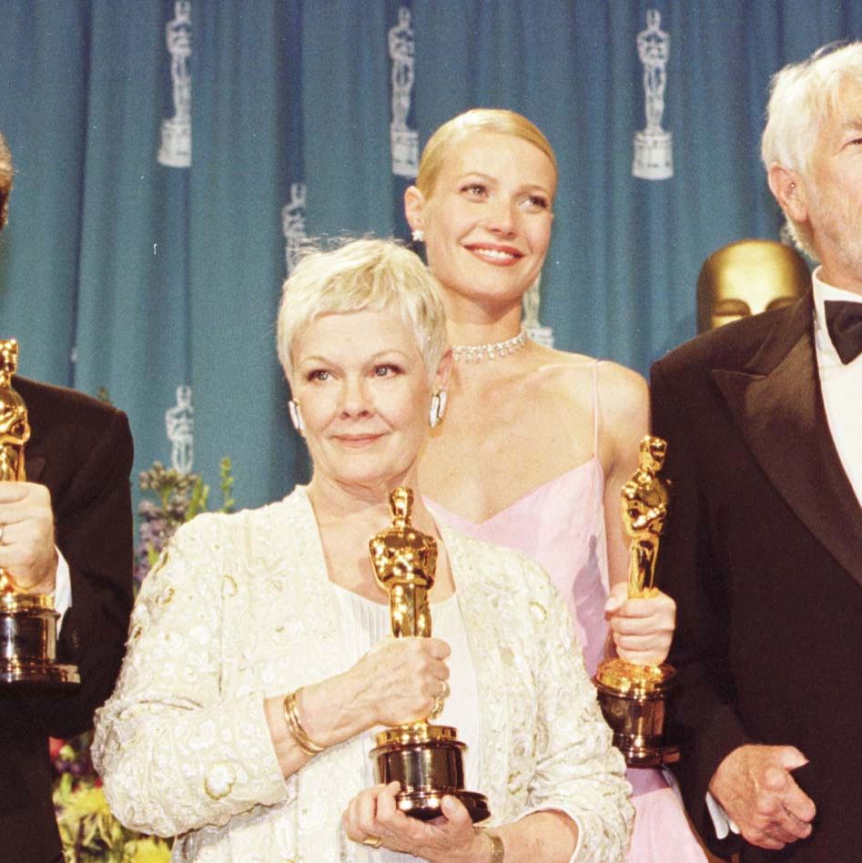 judi dench holding her oscar trophy amid a group of other winners