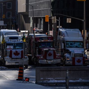 topshot   a woman swalks before vehicles blocking a road during a protest by truck drivers over pandemic health rules and the trudeau government, outside the parliament of canada in ottawa on february 14, 2022 photo by ed jones  afp photo by ed jonesafp via getty images