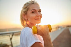 een oudere vrouw is buiten aan het sporten en houdt en gewichtje vast