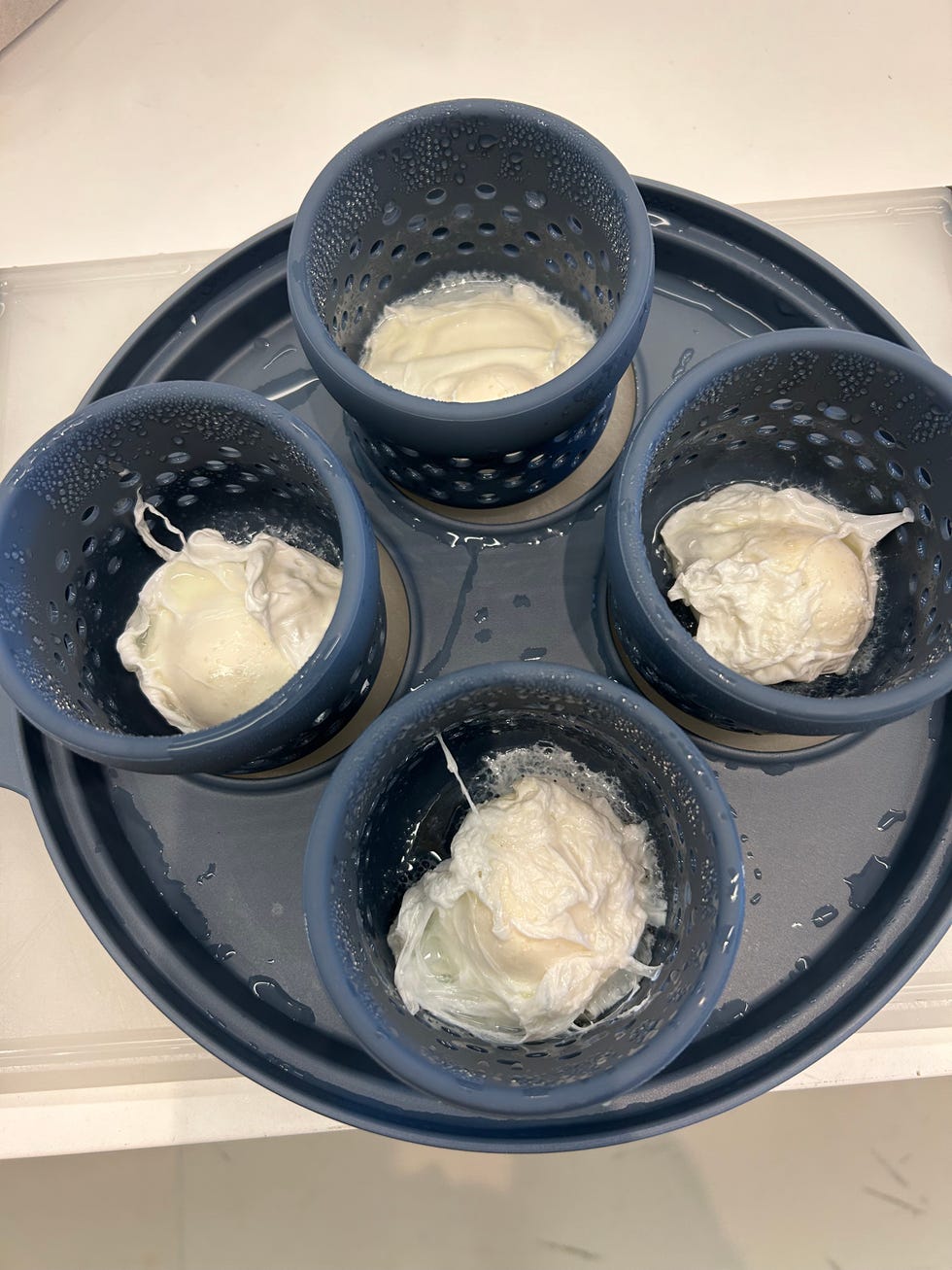 four cups filled with poached eggs in the our place insert