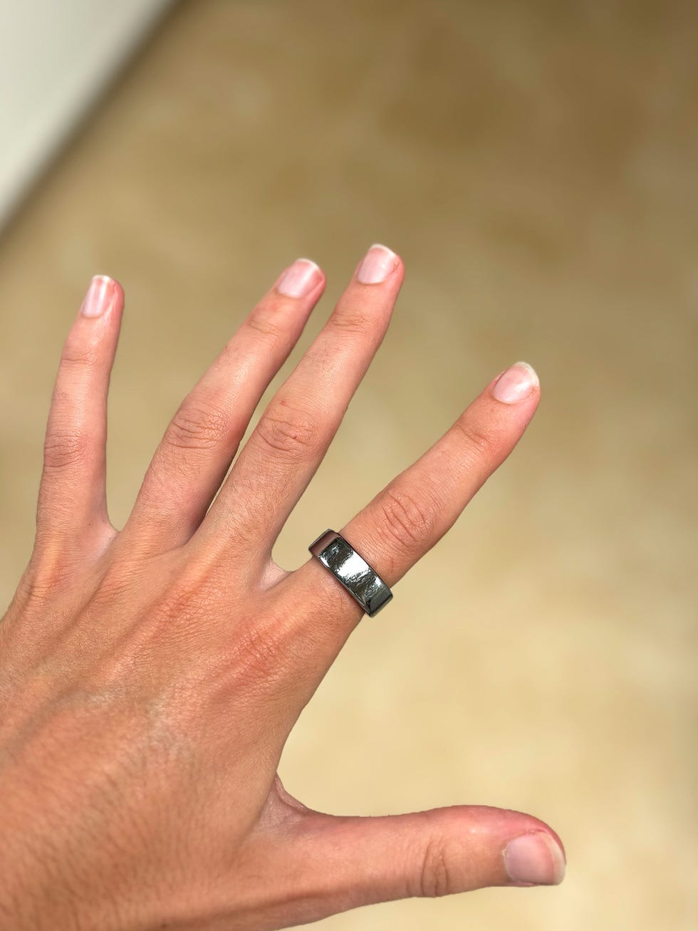 a hand wearing a silver smart ring