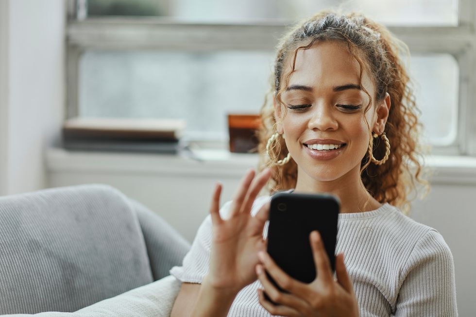 black woman with smartphone on a sofa for networking online, mobile app or relax chat with home wifi young person on couch using phone for internet, social media post or email communication update