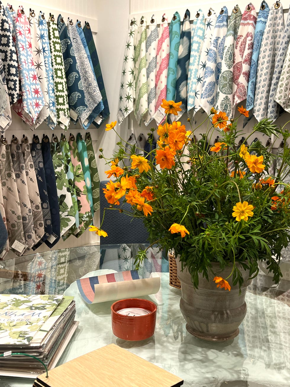 large bouquet of wildflowers on a table in front of rows of hanging fabric samples in several bright colors and patterns