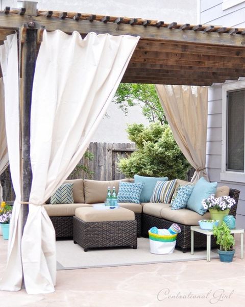 private pergola with curtains around a patio sectional and ottoman