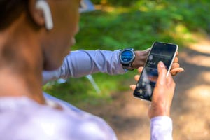 vrouw kijkt op sporthorloge en telefoon voor hartslag