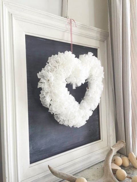 white, fluffy heart shaped wreath hanging against a framed square blackboard