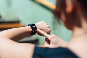 over the shoulder view of young active woman using exercise tracking app on smartwatch to monitor her training progress after running