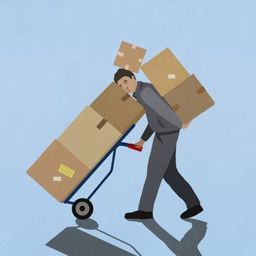 overburdened delivery man carrying cardboard boxes