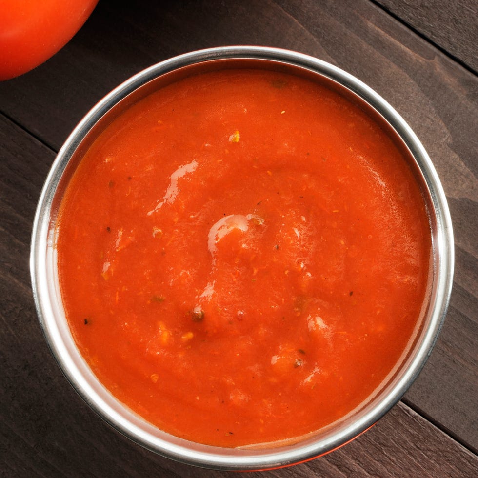 Overhead view of a bowl of tomato sauce next to tomatoes Overhead view of a bowl of tomato sauce next to tomatoes