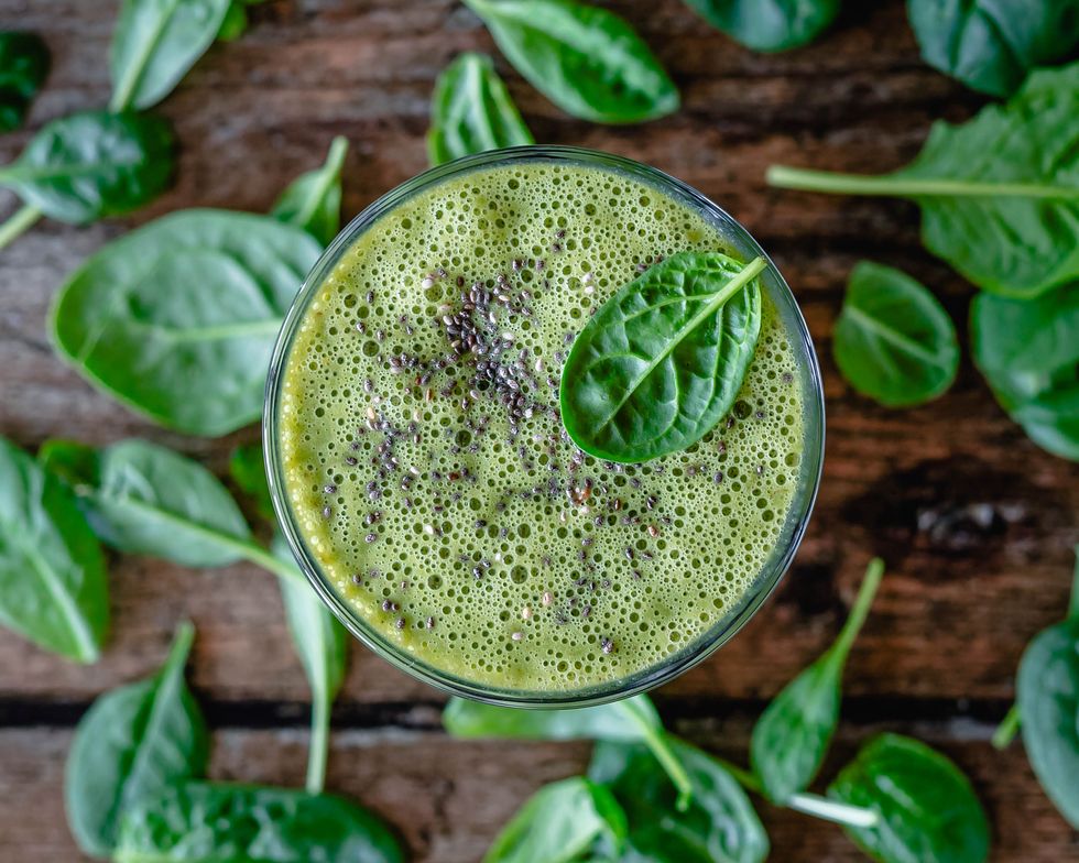 overhead view of a green smoothie with chia seeds and spinach leaves