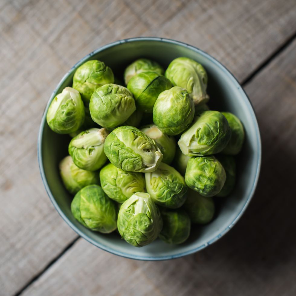 overhead view of bowl of brussels sprouts on wooden background