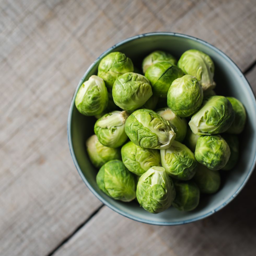 overhead view of bowl of brussels sprouts on wooden background