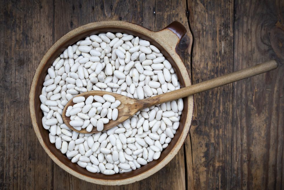overhead view of bowl of white cannellini beans on wooden table