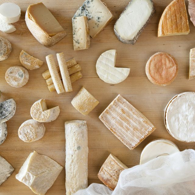 overhead view of hands cutting multiple cheeses