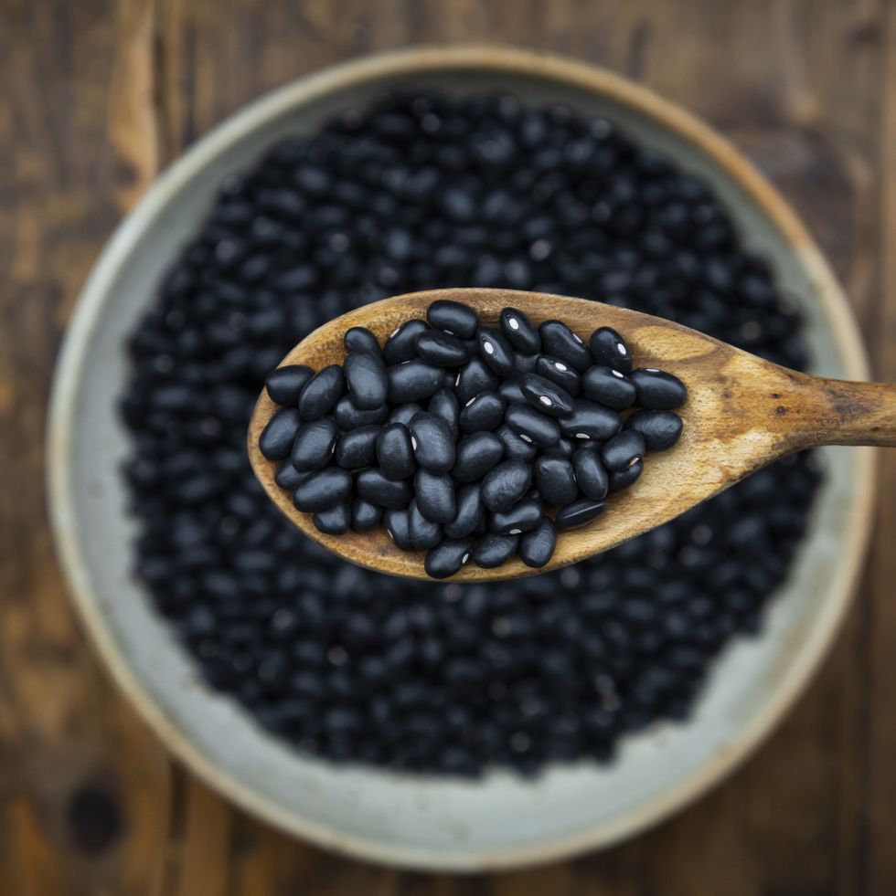 overhead view of spoon and bowl of black bean on wooden table